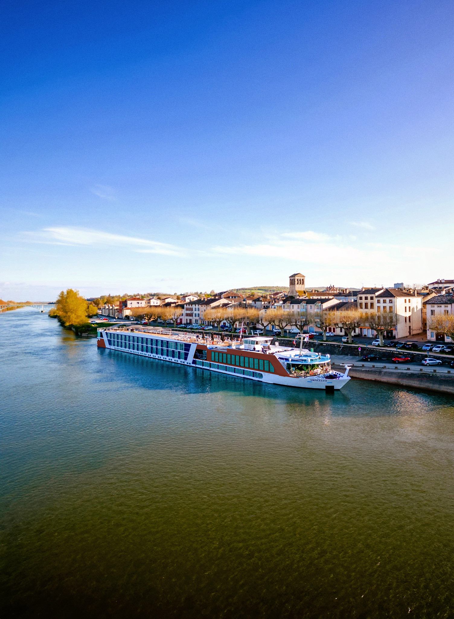 AmaCello river cruise ship sailing past a riverside town in France